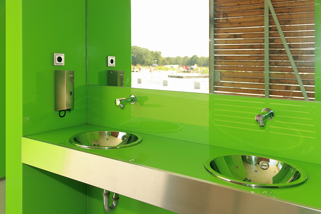 Die Farbglas-Verkleidung in Grüntönen bringt Frische in den Sanitärbereich.